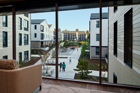 A view from a window of a courtyard with people skating.