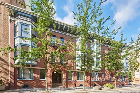 A red brick building with a green tree in front.