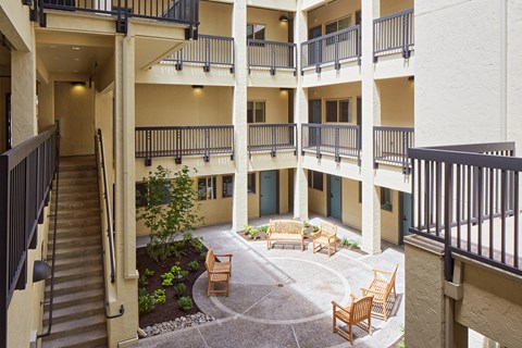 A courtyard with a bench and a tree in the middle of it.