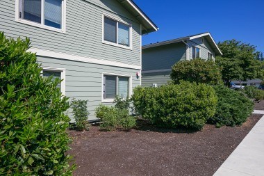 A grey house with a brown gravel area in front.