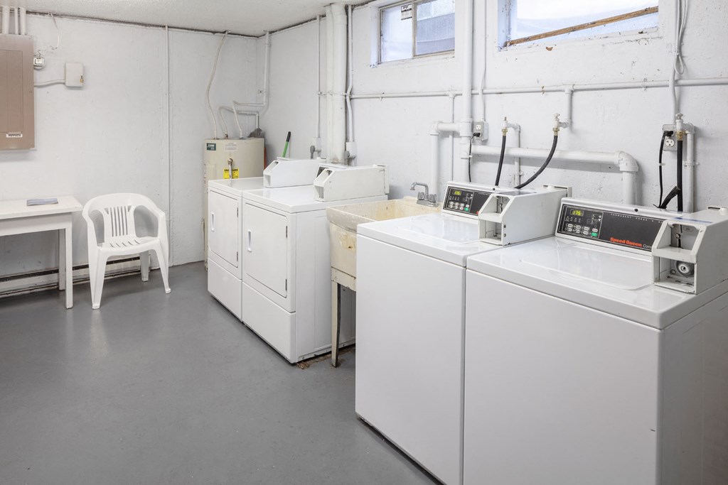 a laundry room with four washing machines and a desk with a chair