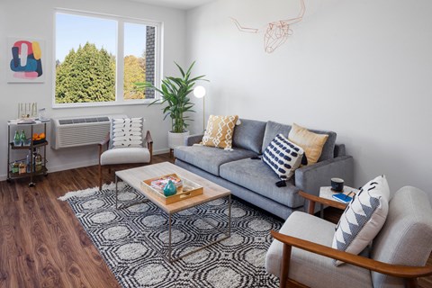 a living room with a couch and two chairs and a window