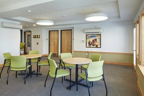 A conference room with green chairs and a white table.