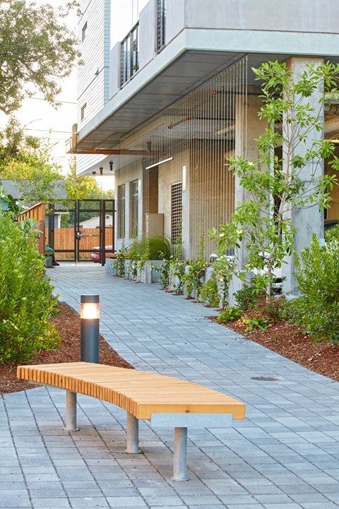 A wooden bench with a metal frame is on a paved walkway.
