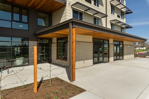 A modern building with a wooden overhang and glass doors.