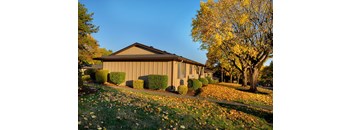 A building with a brown roof and a yellow tree in front of it.