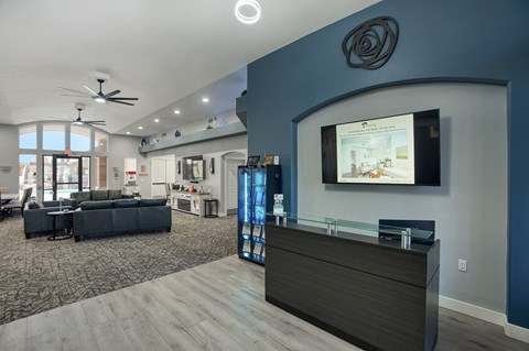 A modern living room with a dark sofa set and a flat screen TV mounted on the wall.