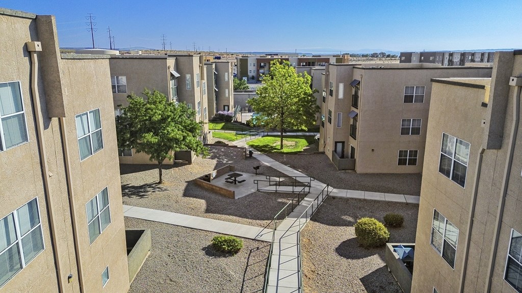 A view of a courtyard from a high angle with a tree, benches, and a small fountain.