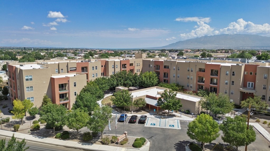 A large apartment complex with a parking lot in front.