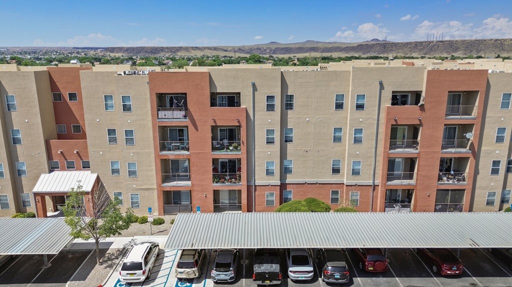 A parking lot in front of a building with a tree.