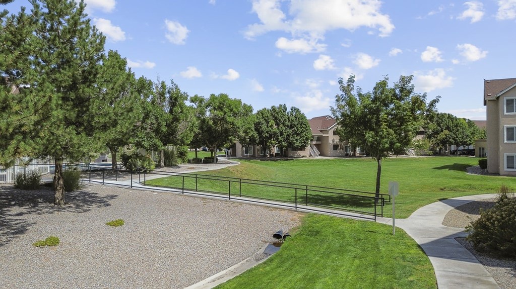 A park area with a gravel playground and a green lawn.
