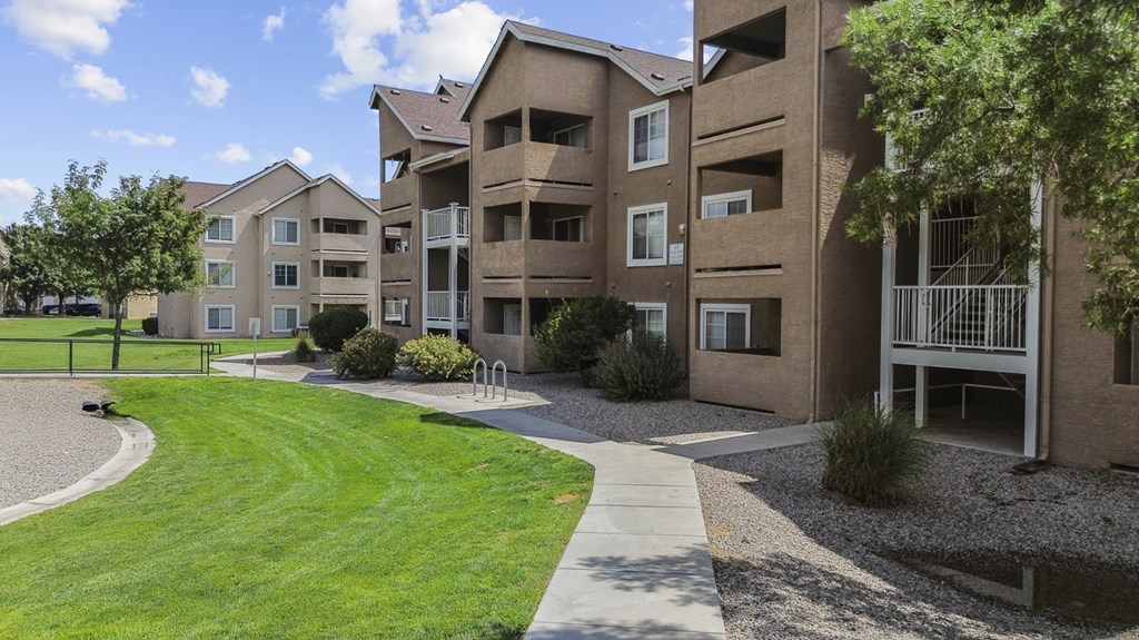 Apartment complex with a green lawn and a walkway.
