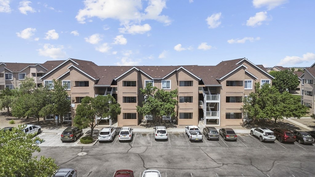 A parking lot in front of a building with cars parked.