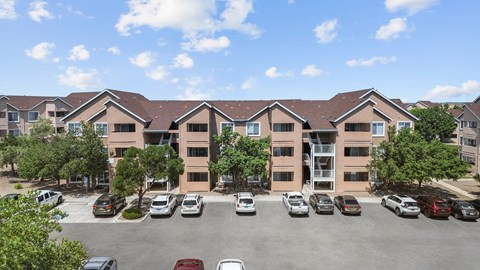 A parking lot in front of a building with cars parked.