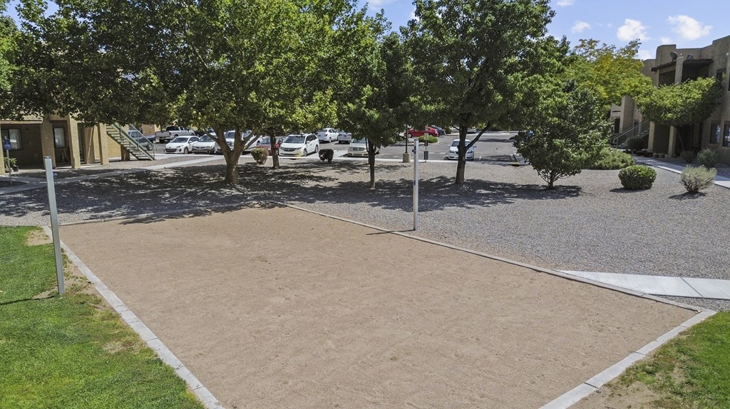 A parking lot with a few cars and trees.