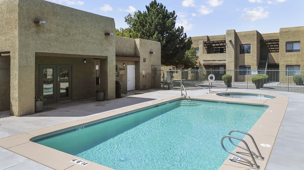 A swimming pool in front of a building with a fence around it.