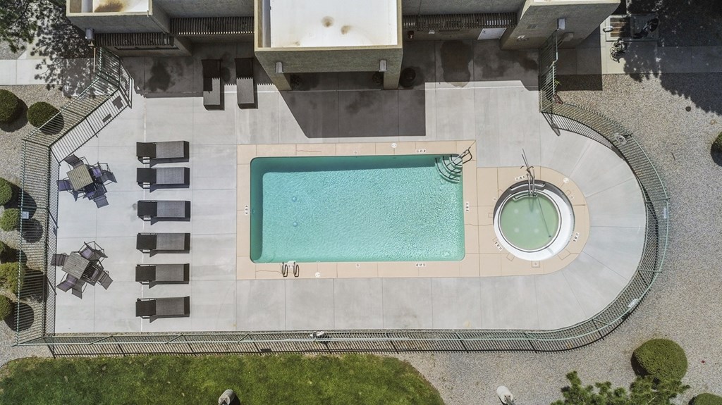 A swimming pool with a hot tub in the middle of a backyard.