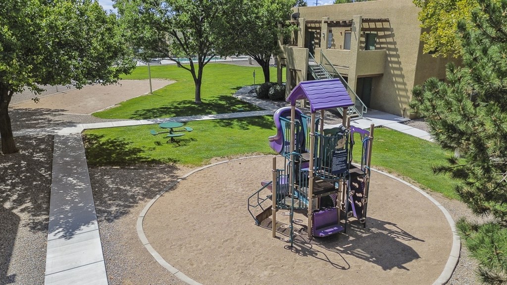 A playground with a purple slide and a round sandbox.
