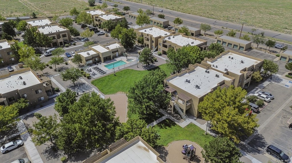 A bird's eye view of a residential area with houses, a pool, and a parking lot.