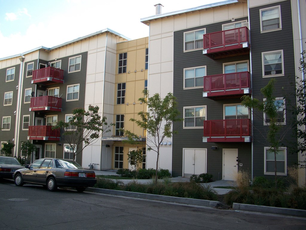 an image of an apartment building with cars parked in front