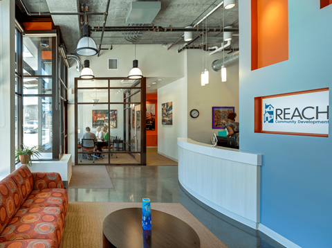 A brightly lit office space with a reception desk and a sofa.