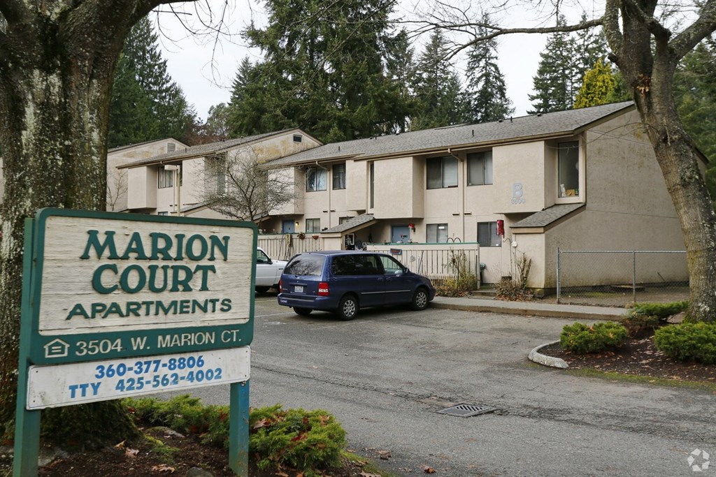 A sign for Marion Court Apartments is in front of a building.