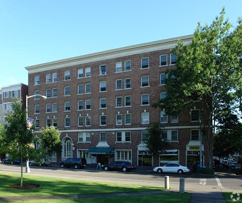 A large brick building with a green awning sits on a street corner.
