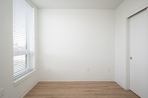 a bedroom with a large window and a wooden floor