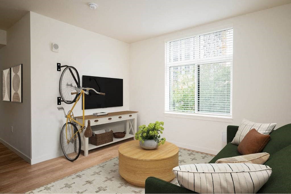 a living room with a green couch and a kitchen with a fan and a window