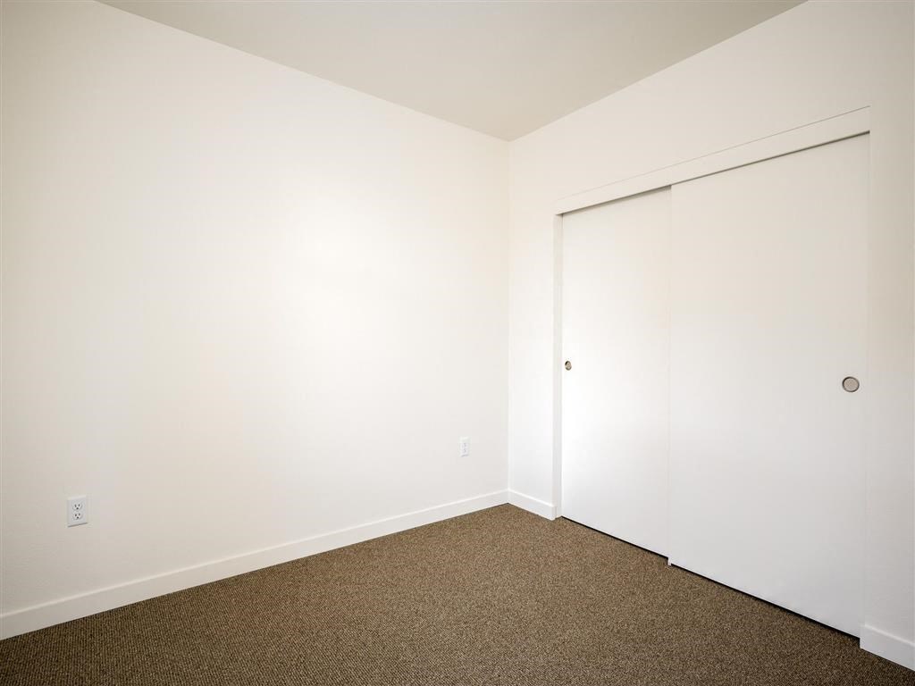 a bedroom with white walls and a door to a closet