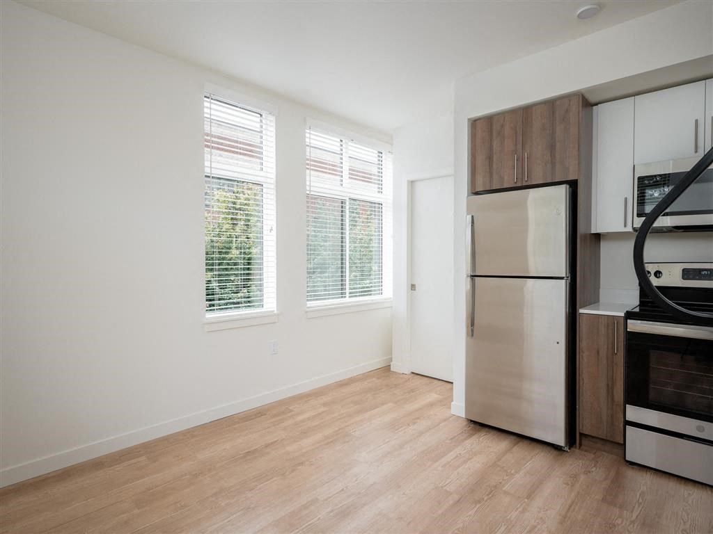 an empty kitchen with a stainless steel refrigerator and a window