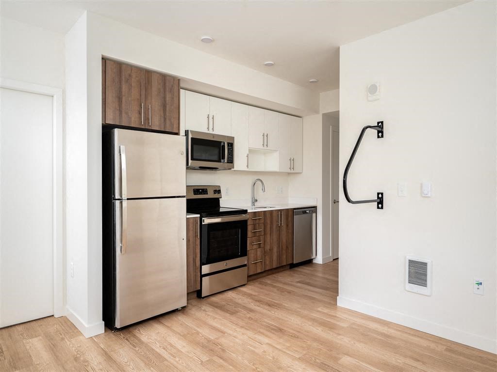 a kitchen with stainless steel appliances and a wood floor in an apartment