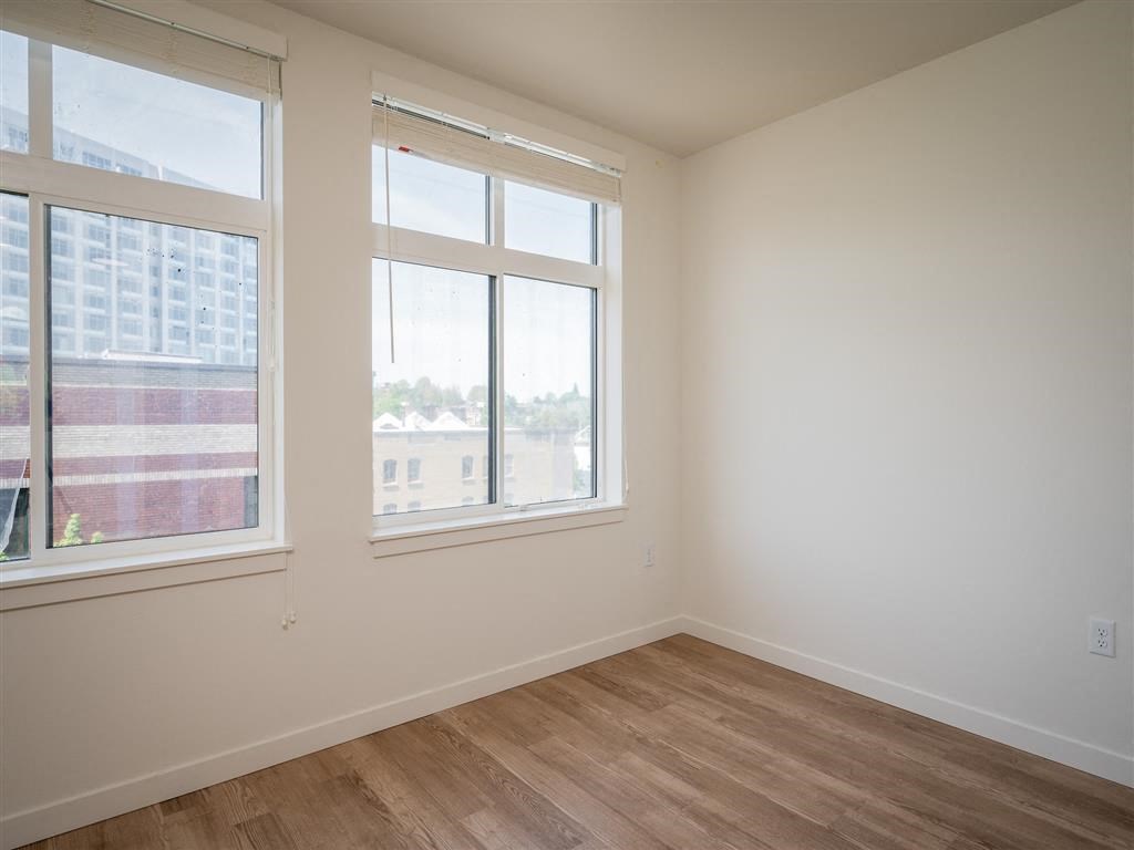 an empty room with three windows and a wooden floor