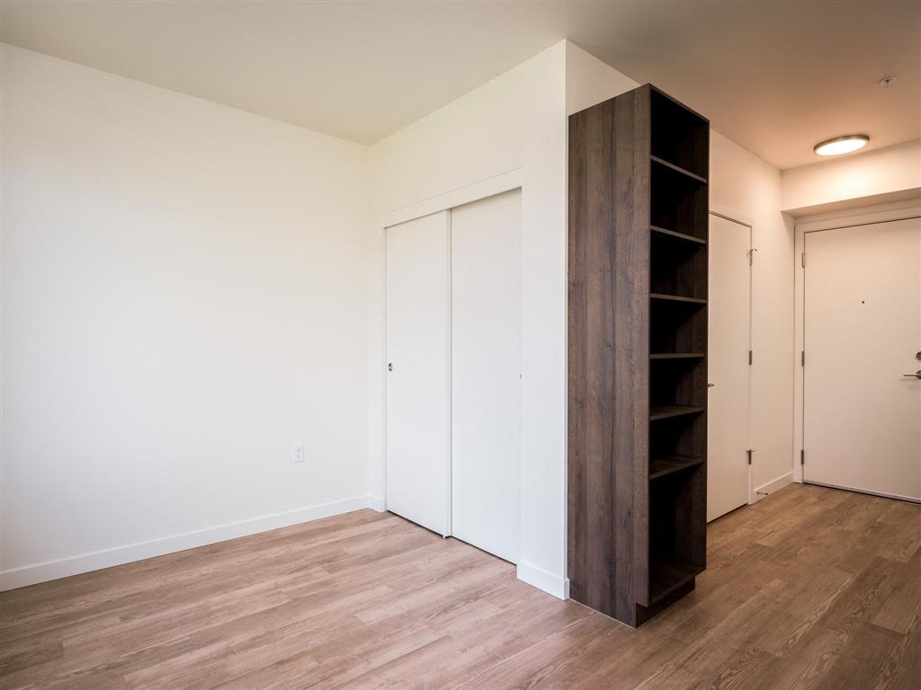 a bedroom with white walls and wood flooring and a close