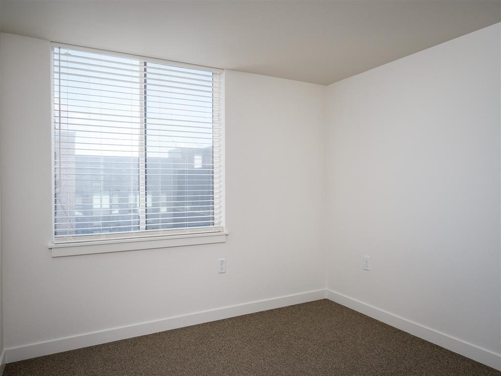 an empty room with a large window and white walls