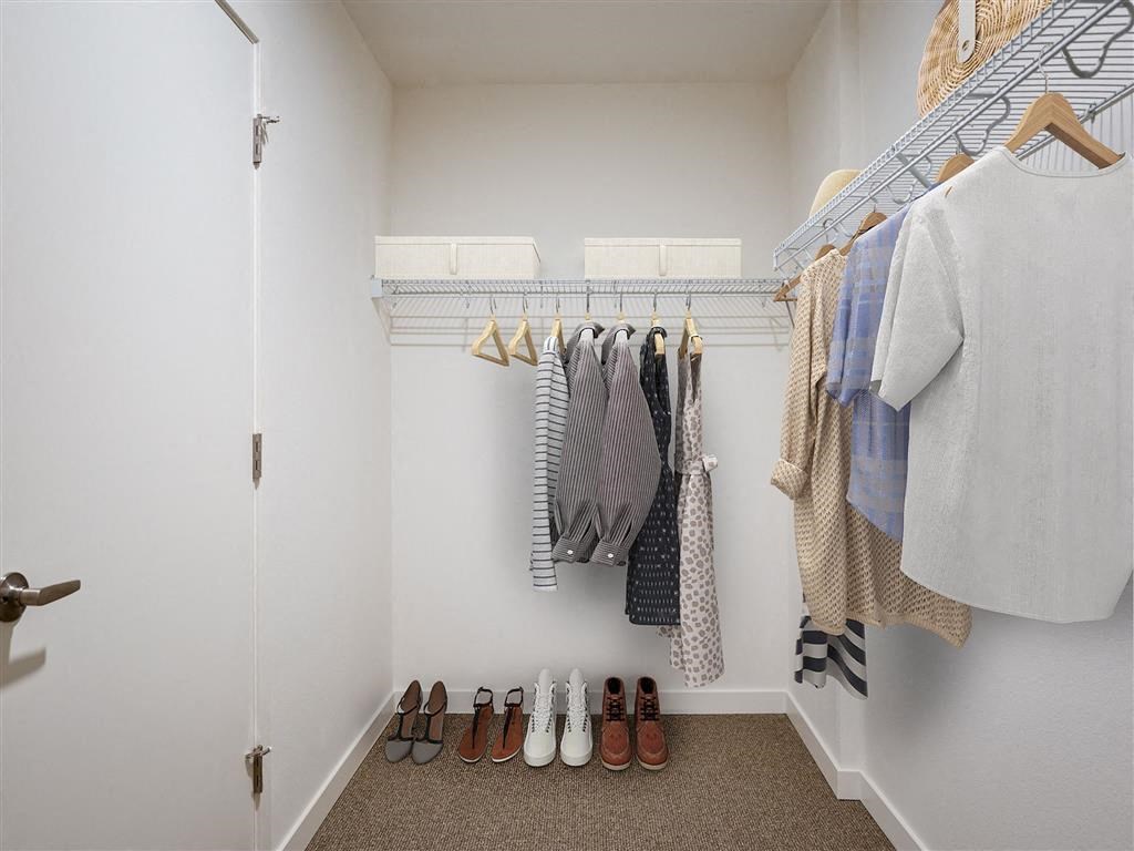 a walk in closet with a rack of clothes and shoes