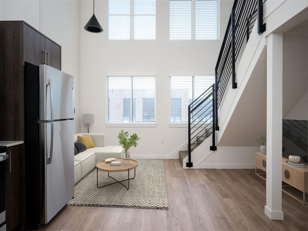 a living room with a refrigerator and a staircase