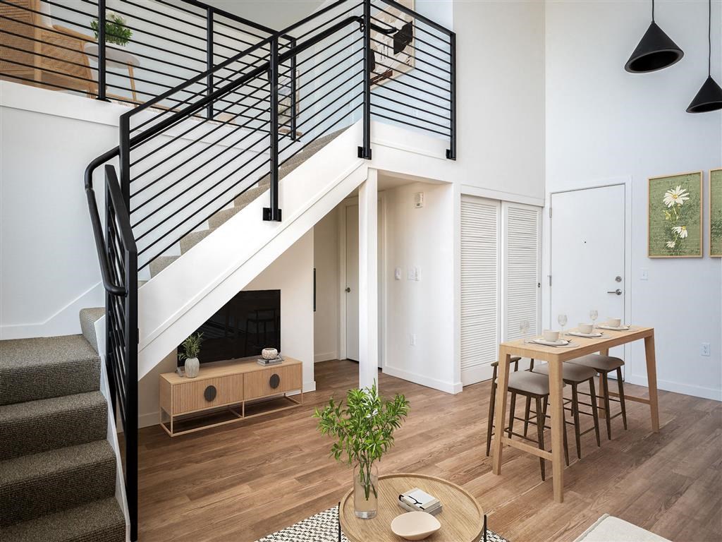 a living room with a staircase and a dining table