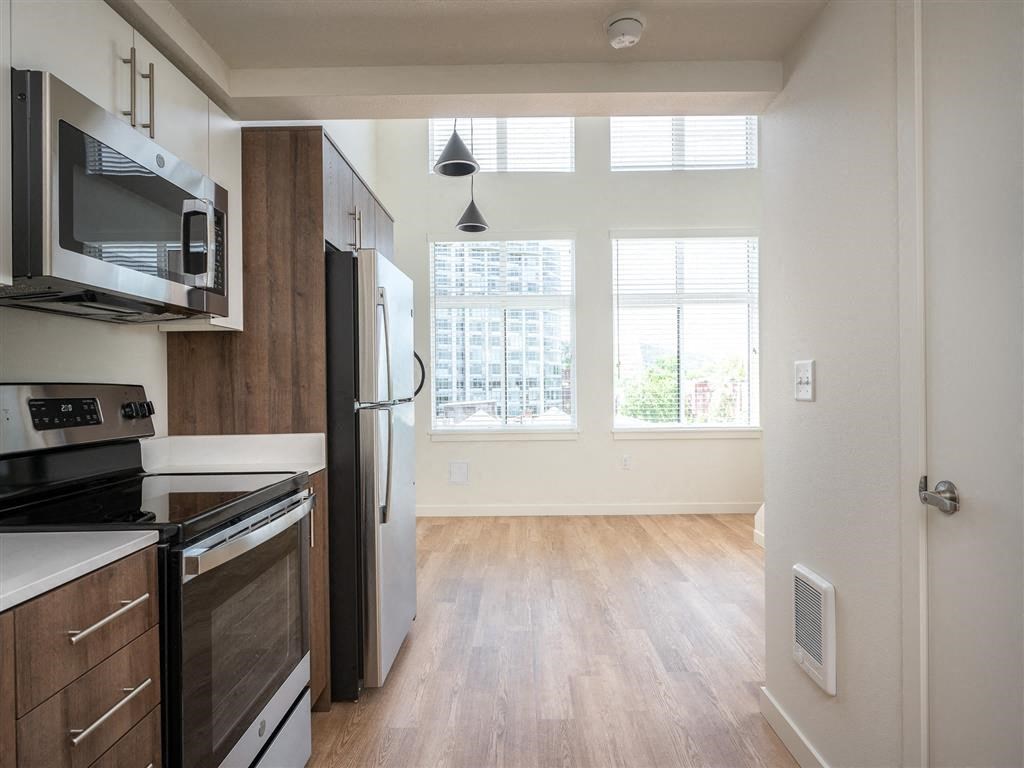 an empty kitchen and living room with a stove refrigerator and microwave
