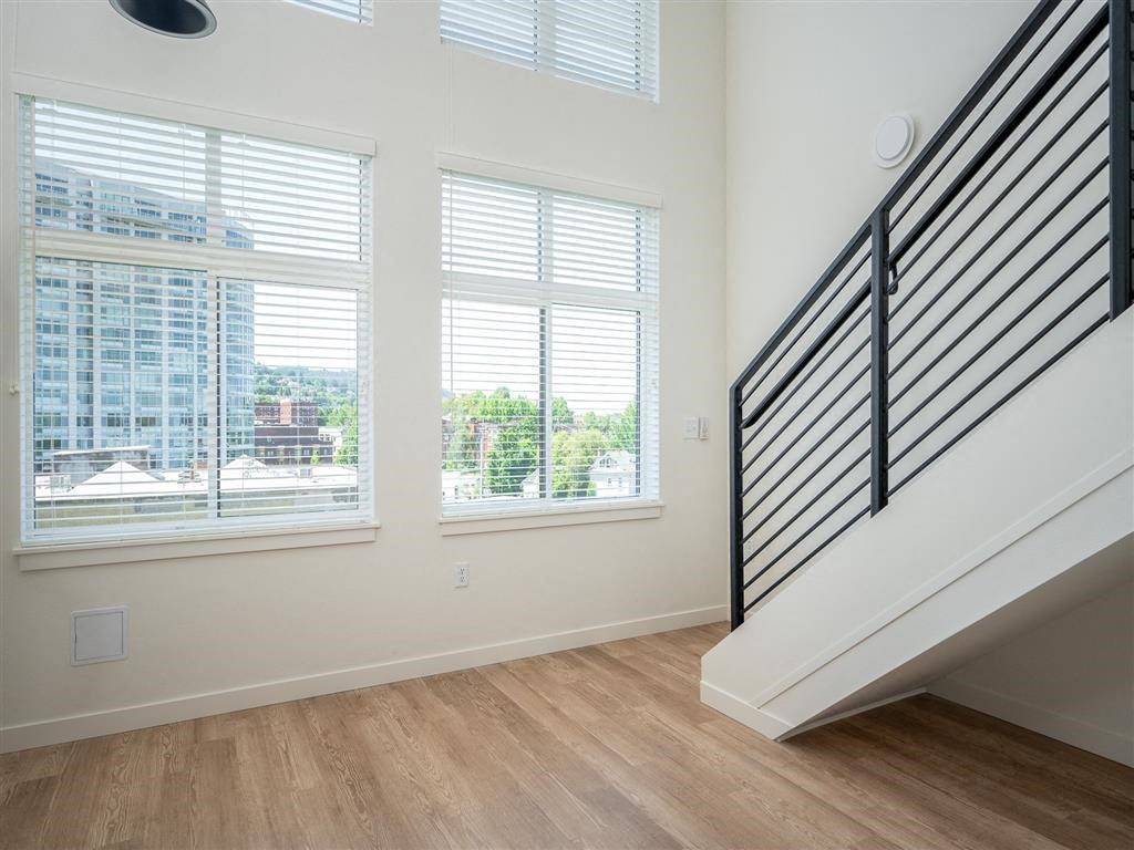 a living room with three windows and a staircase