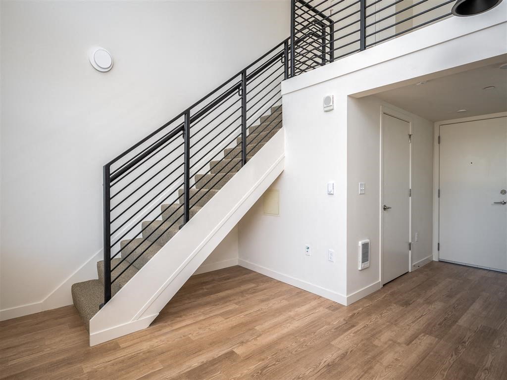 a view of a stairwell in a home with white walls and wood floors