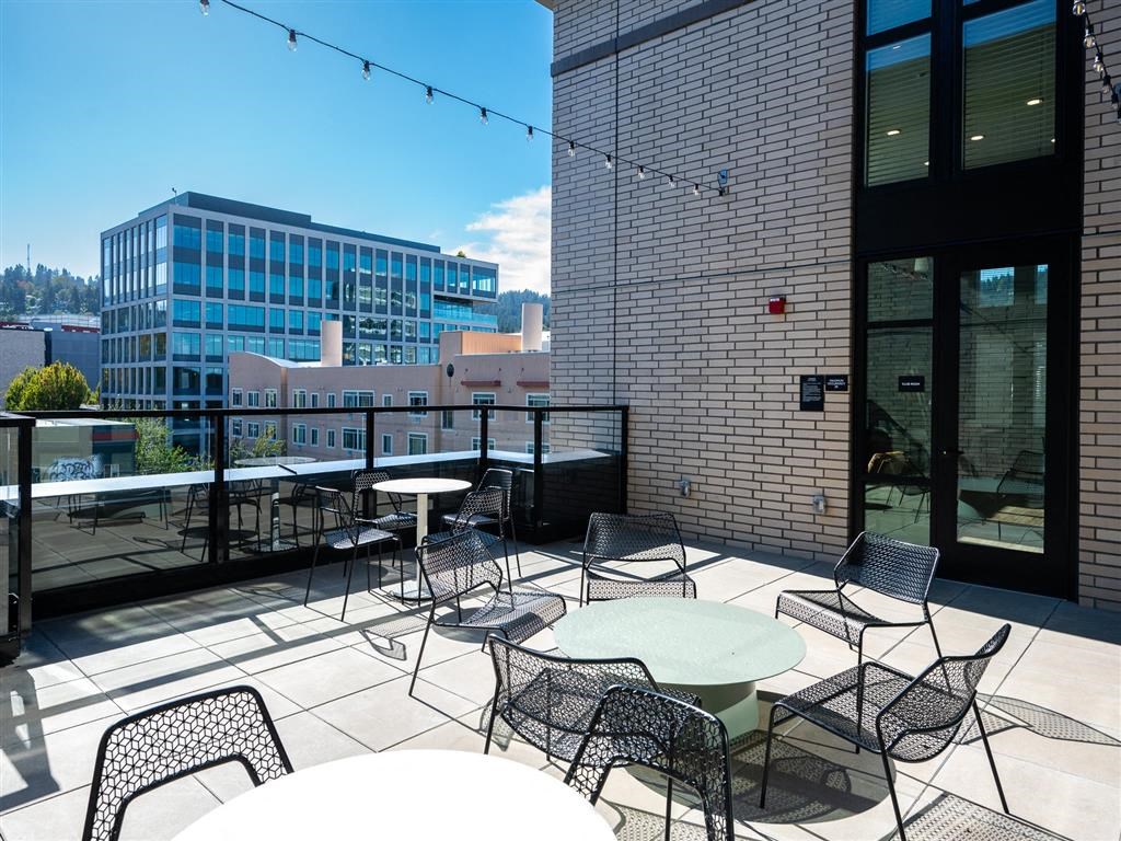 a rooftop patio with tables and chairs and a city in the background
