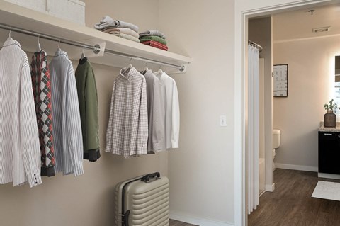 a closet with clothes hanging on a rack and a suitcase
