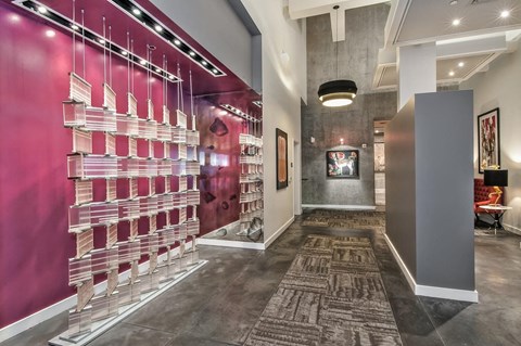 a long hallway with a pink wall and a glass case with pink and white bottles