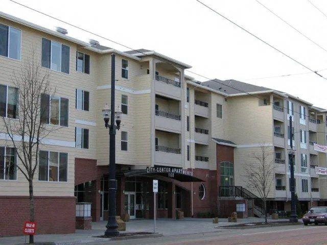 A street view of a multi-story apartment building with a sign that reads "GIT-SET-SEATER APARTMENTS".
