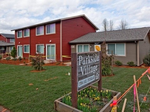 A sign that says Parkside Village stands in front of a building.