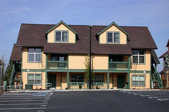 a large yellow house with a parking lot