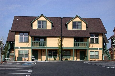 a large yellow house with a parking lot
