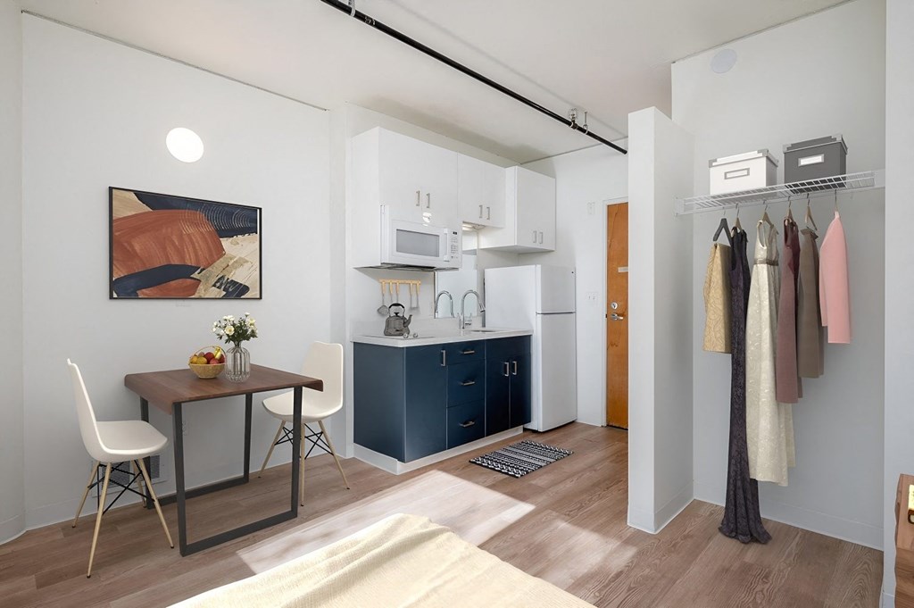 a small room with a desk and a kitchen in it