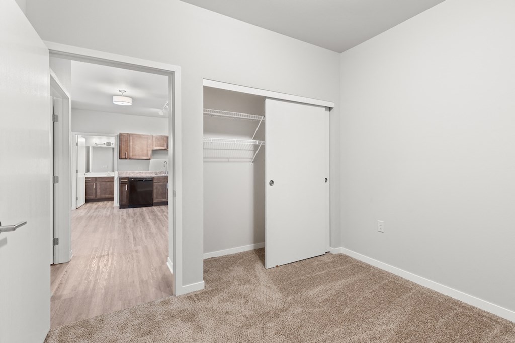 a large carpeted bedroom with a double closet with built-in shelving